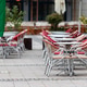 Outdoor cafe with empty red chairs and metal tables stands quietly on a paved street. Outdoor cafe with empty red chairs and metal tables stands quietly on a paved street. - PhotoDune Item for Sale