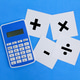 calculator and white paper with plus, minus, multiply, divide signs ...