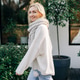 Happy blonde woman wearing a scarf and sweater in the garden in cool weather. Happy blonde woman wearing a scarf and sweater in the garden in cool weather. - PhotoDune Item for Sale