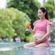 A pregnant woman in a red swimsuit relaxes in a pool while holding a glass of orange juice. A pregnant woman in a red swimsuit relaxes in a pool while holding a glass of orange juice. - PhotoDune Item for Sale