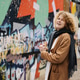 Cheerful woman with curly hair standing near colorful graffiti wall in the city Cheerful woman with curly hair standing near colorful graffiti wall in the city - PhotoDune Item for Sale