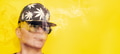 Girl in sunglasses and cap with leaves of marijuana smokes on yellow background Girl in sunglasses and cap with leaves of marijuana smokes on yellow background - PhotoDune Item for Sale