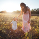 Mother and toddler walking hand in hand through a sunlit field Mother and toddler walking hand in hand through a sunlit field - PhotoDune Item for Sale
