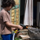 A young boy with curly brown hair sprays water from a hose onto a surface outside a house. A young boy with curly brown hair sprays water from a hose onto a surface outside a house. - PhotoDune Item for Sale