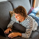 Young man lying on sofa at home using laptop Young man lying on sofa at home using laptop - PhotoDune Item for Sale