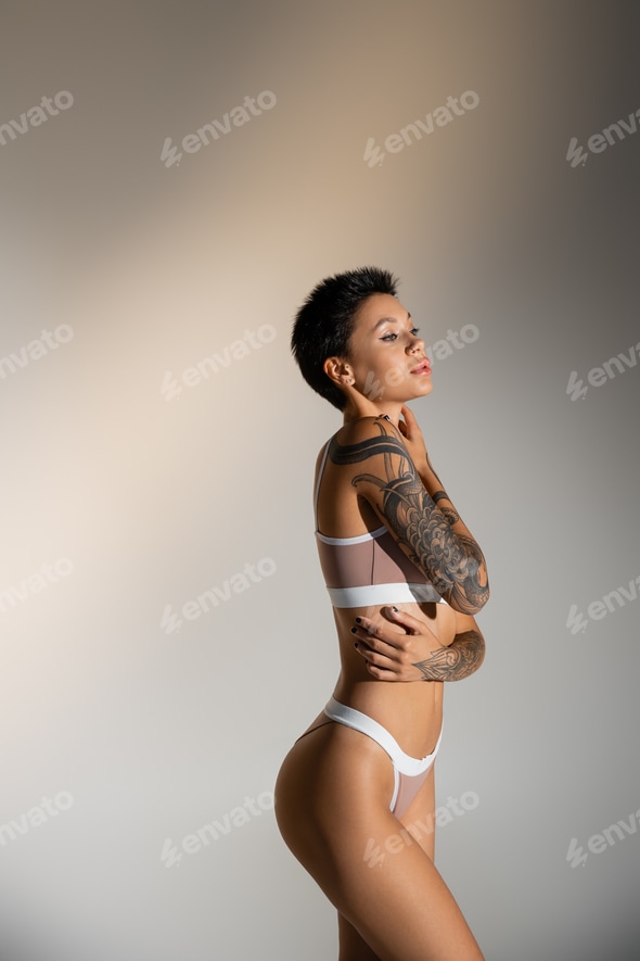 side view of sexy tattooed woman in underwear touching perfect body on grey background Stock Photo by LightFieldStudios side view of sexy tattooed woman in underwear touching perfect body on grey background Stock Photo by LightFieldStudios
