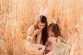 Two little girls sisters sitting in wheat field collecting red eggs in basket. Celebrating Easter Two little girls sisters sitting in wheat field collecting red eggs in basket. Celebrating Easter - PhotoDune Item for Sale