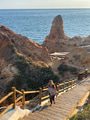 Woman climbing a long staircase with blue sea & rock formations in distance diminishing perspective Woman climbing a long staircase with blue sea & rock formations in distance diminishing perspective - PhotoDune Item for Sale