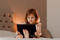 Toddler girl sitting in bedroom, using laptop tablet pad gadget, watching with focused face Toddler girl sitting in bedroom, using laptop tablet pad gadget, watching with focused face - PhotoDune Item for Sale