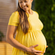 Smiling pregnant woman in yellow dress enjoying outdoors on sunny day Smiling pregnant woman in yellow dress enjoying outdoors on sunny day - PhotoDune Item for Sale
