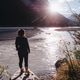 Woman standing on boulder over looking a sunlit river scene with the sun rays peeking over the Woman standing on boulder over looking a sunlit river scene with the sun rays peeking over the - PhotoDune Item for Sale