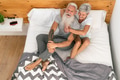 Happy senior couple smiling together in bed Happy senior couple smiling together in bed - PhotoDune Item for Sale