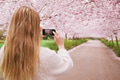 Young woman shooting spring blossom garden with mobile phone Young woman shooting spring blossom garden with mobile phone - PhotoDune Item for Sale