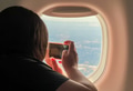 Unrecognized woman taking photos with mobile device of landscapes viewed through airplane's window Unrecognized woman taking photos with mobile device of landscapes viewed through airplane's window - PhotoDune Item for Sale
