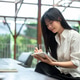 Asian woman freelancer holding pen writing in notebook over table while sitting on sofa in a cafe. Asian woman freelancer holding pen writing in notebook over table while sitting on sofa in a cafe. - PhotoDune Item for Sale