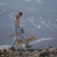 A girl walks behind a dog on a leash against the backdrop of winter mountains A girl walks behind a dog on a leash against the backdrop of winter mountains - PhotoDune Item for Sale