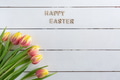 Easter greeting card template with Happy Easter text and tulips on white wooden background, flat lay Easter greeting card template with Happy Easter text and tulips on white wooden background, flat lay - PhotoDune Item for Sale