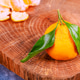 Orange fruit with green leaves on wooden cutting board in kitchen setting with peeled segments Orange fruit with green leaves on wooden cutting board in kitchen setting with peeled segments - PhotoDune Item for Sale