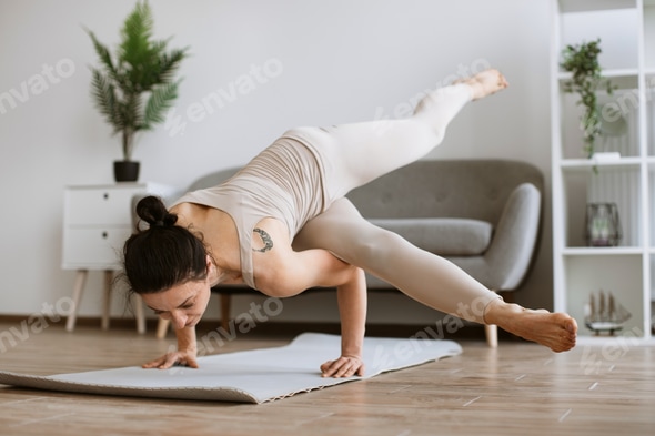Mature woman in an advanced horizontal handstand yoga pose at home