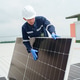 Worker installs solar panels on roof during daytime in a commercial area Worker installs solar panels on roof during daytime in a commercial area - PhotoDune Item for Sale