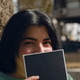 Portrait of young woman in park sitting on her face with book Portrait of young woman in park sitting on her face with book - PhotoDune Item for Sale