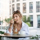 Elegant Female Sitting at a Cafe Table with Layered Cake, Hot Drink, and Urban Greenery Around Elegant Female Sitting at a Cafe Table with Layered Cake, Hot Drink, and Urban Greenery Around - PhotoDune Item for Sale