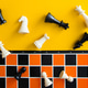Chess pieces falling on orange board against yellow background Chess pieces falling on orange board against yellow background - PhotoDune Item for Sale