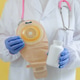 One doctor holds a colostomy bag and a white bottle of pills. One doctor holds a colostomy bag and a white bottle of pills. - PhotoDune Item for Sale