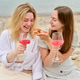 Young women enjoying pink wine and pizza at beach picnic Young women enjoying pink wine and pizza at beach picnic - PhotoDune Item for Sale