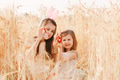 Two little girls sisters sitting in wheat field collecting red eggs in basket. Celebrating Easter Two little girls sisters sitting in wheat field collecting red eggs in basket. Celebrating Easter - PhotoDune Item for Sale