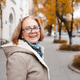 Smiling senior woman 55-60 year old with gray hair wearing eye glasses walking in city street Smiling senior woman 55-60 year old with gray hair wearing eye glasses walking in city street - PhotoDune Item for Sale