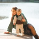 Cute mother holding baby 1-2 year old wearing knitted sweater sitting on wooden pier over lake Cute mother holding baby 1-2 year old wearing knitted sweater sitting on wooden pier over lake - PhotoDune Item for Sale