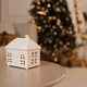 Small ceramic house shaped candle on table over Christmas lights in room close up. Winter holiday se Small ceramic house shaped candle on table over Christmas lights in room close up. Winter holiday se - PhotoDune Item for Sale