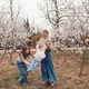 Happy mother with two child girls wearing denim clothes holding hands over blooming trees in park Happy mother with two child girls wearing denim clothes holding hands over blooming trees in park - PhotoDune Item for Sale