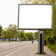 A blank billboard is present next to a road. There are trees lining the street and a sidewalk. The s A blank billboard is present next to a road. There are trees lining the street and a sidewalk. The s - PhotoDune Item for Sale