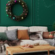 A warm living room features a sofa with colorful pillows and a green wall. A wreath hangs above, whi A warm living room features a sofa with colorful pillows and a green wall. A wreath hangs above, whi - PhotoDune Item for Sale