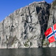 The national flag of Norway waving on a tour boat with a massive steep granite cliff of Lysefjord in The national flag of Norway waving on a tour boat with a massive steep granite cliff of Lysefjord in - PhotoDune Item for Sale