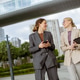 Women share ideas while walking in a city park near modern buildings and a bridge Women share ideas while walking in a city park near modern buildings and a bridge - PhotoDune Item for Sale