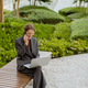 Woman works on laptop while talking on phone in a park setting during the day Woman works on laptop while talking on phone in a park setting during the day - PhotoDune Item for Sale