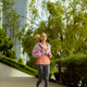 Young woman runs in urban park during morning hours near tall buildings Young woman runs in urban park during morning hours near tall buildings - PhotoDune Item for Sale