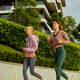 Women jog along a path in an urban area with buildings and green plants in view Women jog along a path in an urban area with buildings and green plants in view - PhotoDune Item for Sale