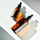 Amber dropper bottles holding skincare serum in sunlight Amber dropper bottles holding skincare serum in sunlight - PhotoDune Item for Sale