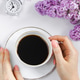 Female hands holding cup of espresso coffee. Alarm clock and lilac flowers on light background. Female hands holding cup of espresso coffee. Alarm clock and lilac flowers on light background. - PhotoDune Item for Sale