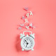 Small retro alarm clock and lilac flowers on pink background. Small retro alarm clock and lilac flowers on pink background. - PhotoDune Item for Sale