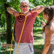 Older man completing a shoulder strengthening exercise using a resistance band under professional su Older man completing a shoulder strengthening exercise using a resistance band under professional su - PhotoDune Item for Sale