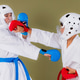 Karate athlete lands a close range punch directly to the opponent's helmeted head while defender att Karate athlete lands a close range punch directly to the opponent's helmeted head while defender att - PhotoDune Item for Sale
