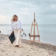 Woman walking along beach with canvas and easel in overcast light Woman walking along beach with canvas and easel in overcast light - PhotoDune Item for Sale