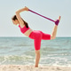 Young woman stretching with purple resistance band on sandy beach by ocean shore Young woman stretching with purple resistance band on sandy beach by ocean shore - PhotoDune Item for Sale