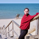 Young woman in red sweater relaxing on wooden beach stairs on sunny day by ocean Young woman in red sweater relaxing on wooden beach stairs on sunny day by ocean - PhotoDune Item for Sale