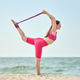 Young woman using purple resistance band for yoga stretch on sandy beach with ocean background Young woman using purple resistance band for yoga stretch on sandy beach with ocean background - PhotoDune Item for Sale
